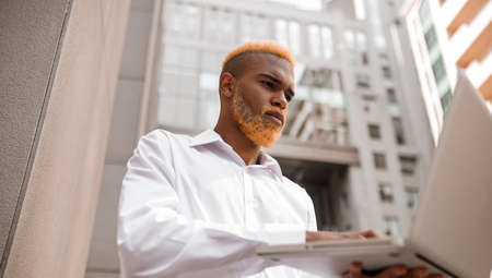 Young dark-skinned man in white clothes looking confidentの写真素材
