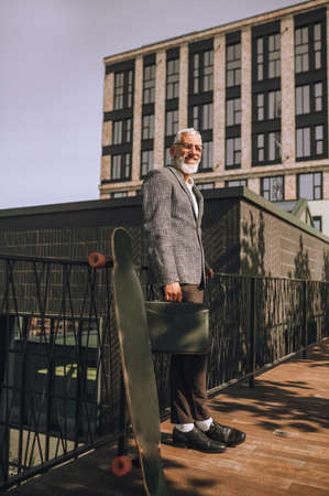 Elegant gray-haired matured man standing on a urban backgroundの写真素材