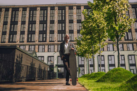 A mature man with a skateboard in the office districtの写真素材