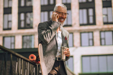 A gray-haired man with a gadget in handsの写真素材