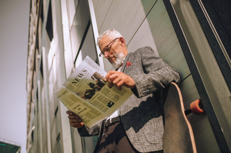 A gray-haired businessman reading a newspaper and looking concentratedの写真素材
