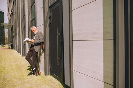 A gray-haired businessman with a newspaper in handsの写真素材