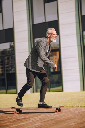 A businessman riding a skateboard in front of the office buildingの写真素材
