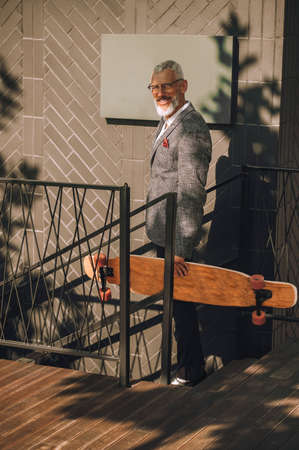A gray-haired businessman with a skateboard in the office district