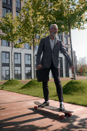 An elegant mature man riding a skateboardの写真素材
