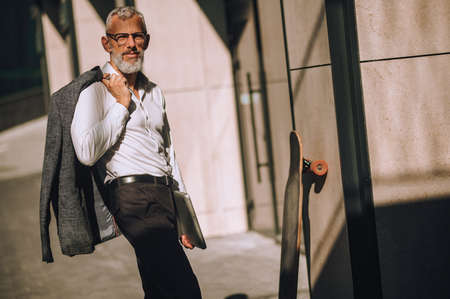 Stylish modern businessman in eyeglasses standing alone outsideの写真素材