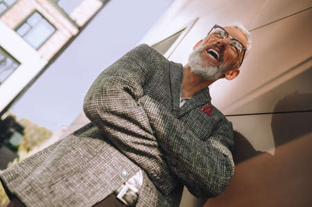 Elegant mature male with his hands folded standing outsideの写真素材