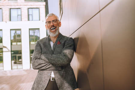 Happy mature bespectacled businessman standing by the wallの写真素材