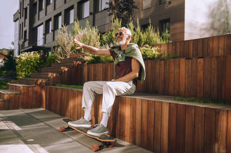 Joyous mature male skateboarder having fun outdoorsの写真素材