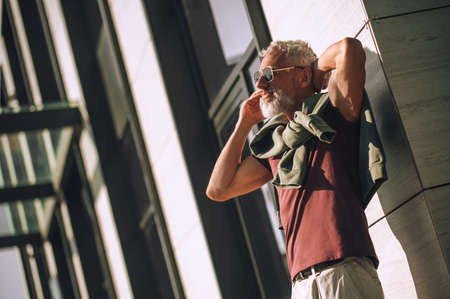 Gray-haired bearded calm male calling on the smartphone