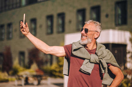 Joyous man photographing himself with his smartphone