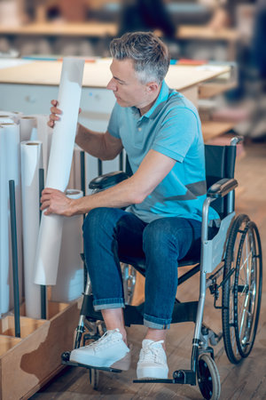 Man in wheelchair taking roll of paperの写真素材
