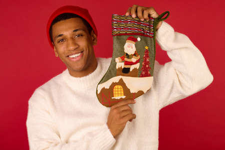 A dark-skinned young guy with a xmas stocking in hands