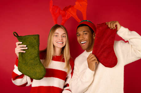 Young people in hats with antlers holding their christmas stockings