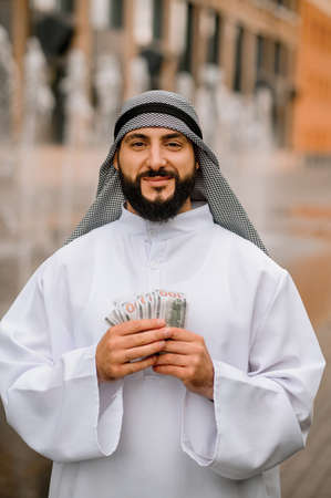 Middle eastern young man holding dollars in handsの写真素材