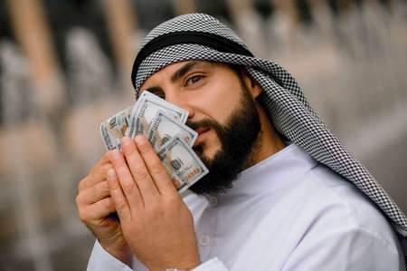 Middle eastern young man holding dollars in handsの写真素材