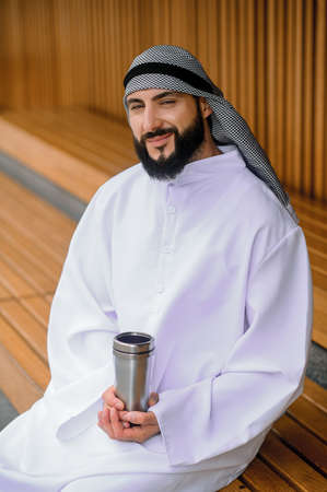 Young arabian man sitting on a wooden bench with metalの写真素材