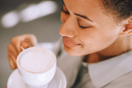 Close up picture of woman enjoying coffee smellの写真素材