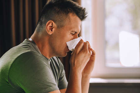 Office worker sitting at the table and sneezing