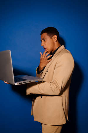 Guy standing sideways to camera looking at laptopの写真素材