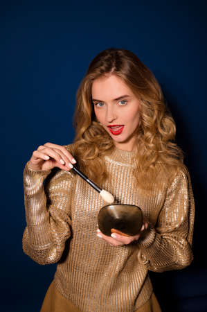 Pretty girl holding brush and powder looking at cameraの写真素材