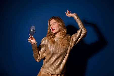 Cheerful girl looking at glass of champagne in handの写真素材