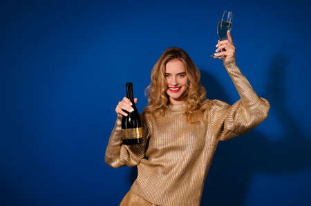 Girl showing bottle of champagne looking at cameraの写真素材