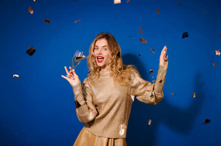 Girl with champagne looking at camera and falling confettiの写真素材