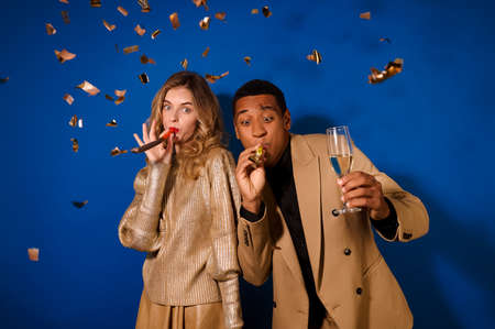 Funny guy and girl blowing festive whistlesの写真素材
