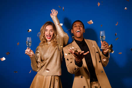 Guy and girl with champagne rejoicing flying confettiの写真素材