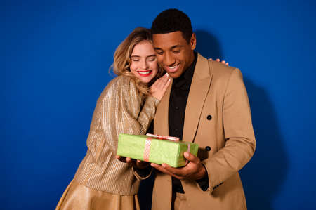 Girl hugging happy guy with giftの写真素材