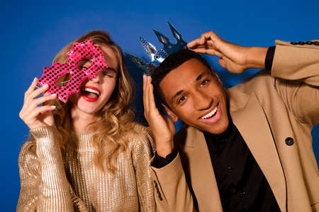 Guy in crown smiling at camera and girl with maskの写真素材
