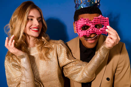 Girl holding mask near face of guy in crownの写真素材