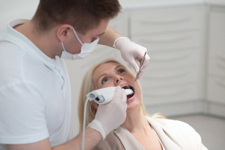 Male dentist doing teeth restoration to a female patientの写真素材