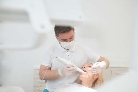 Male dentist doing teeth restoration to a female patientの写真素材