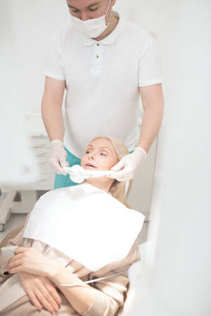 A male dentist preparing his patient to the dental surgeryの写真素材