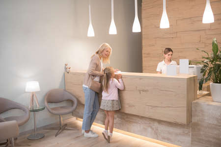 A blonde woman and her daughter waiting for the appointment at the clinicの写真素材