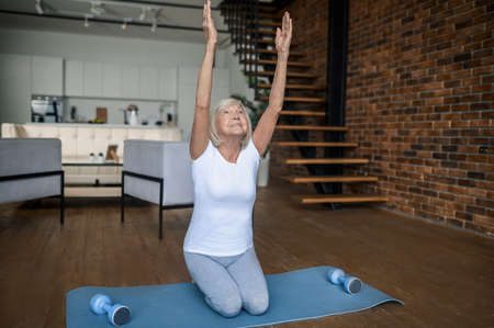 Gray-haired senior woman in sportswear doing stretchingの写真素材