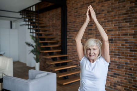 Gray-haired senior woman standing with her arms upの写真素材