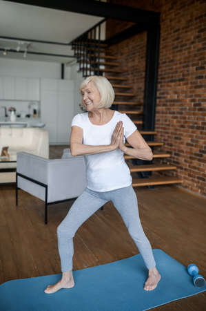 Slim aging woman doing yoga at homeの写真素材