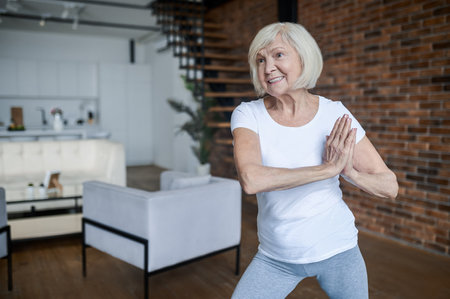 Slim aging woman doing yoga at homeの写真素材