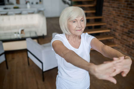 Woman in a white tshirt stretching her arms forwardの写真素材