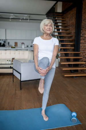 A senior woman doing balancing asana and looking concentratedの写真素材