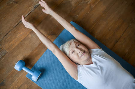 A senior woman laying on the floor and stretchingの写真素材