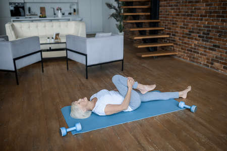 An elderly lady doing yoga at homeの写真素材
