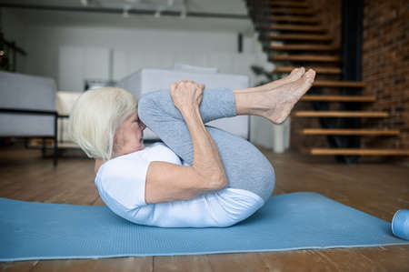 A woman doing exercises while sitting on the yoga matの写真素材