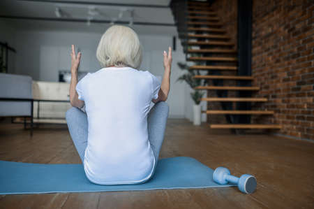 A woman doing exercises while sitting on the yoga matの写真素材