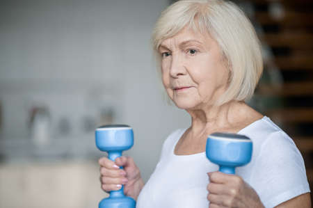 Active senior woman with dumbbells in hands doing her workoutの写真素材