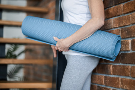 Slim senior woman with yoga mat in handsの写真素材