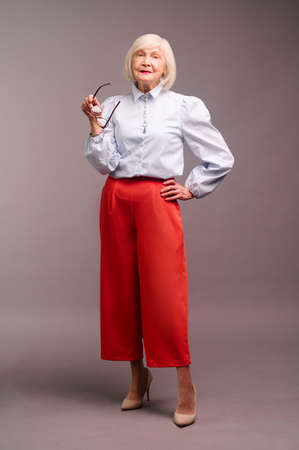 Elegant senior woman in white blouse and red pantsの写真素材